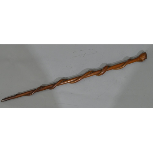 665 - A 19th Century carved wooden walking stick with hand finial clutching entwined end coiled around who... 