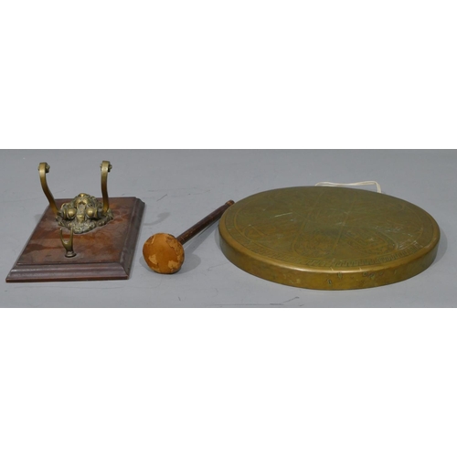 672 - A circular brass hanging gong with hammer mounted on oak panel with lion's head motif, gong 30cm dia... 