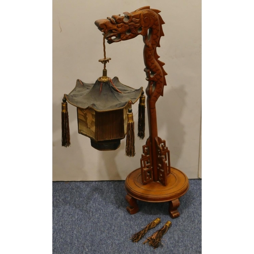 699 - A Chinese hardwood table lamp in the form of a dragon supporting hexagonal shaped lantern with figur... 