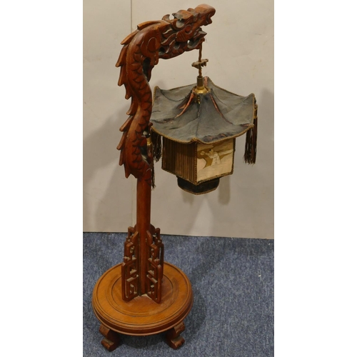 699 - A Chinese hardwood table lamp in the form of a dragon supporting hexagonal shaped lantern with figur... 