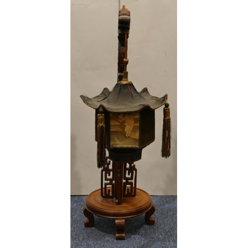 699 - A Chinese hardwood table lamp in the form of a dragon supporting hexagonal shaped lantern with figur... 