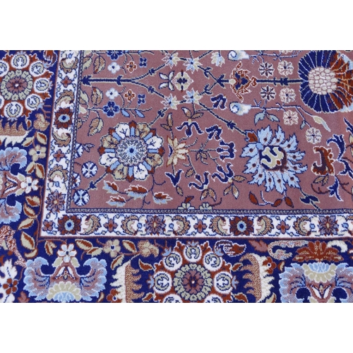 712 - A modern large Persian carpet on light terracotta ground with allover floral, leaf and scroll decora... 