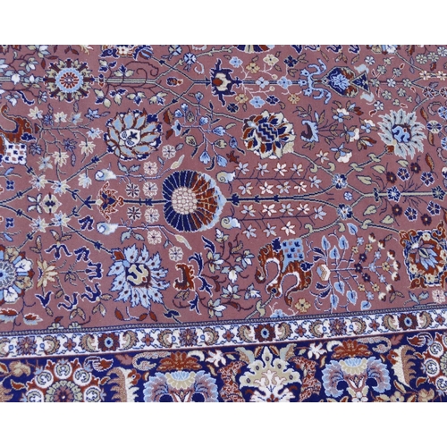 712 - A modern large Persian carpet on light terracotta ground with allover floral, leaf and scroll decora... 