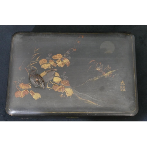 713 - An Oriental lacquered rectangular shaped box on black ground with raised bird, gilt and leaf decorat... 