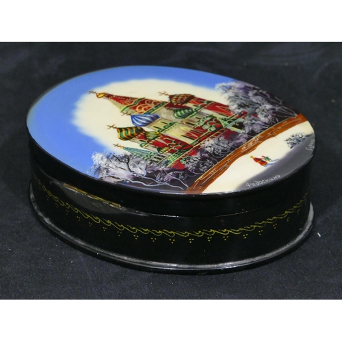 728 - A black lacquered oval box with hinged lid depicting figures in winter scene with Orthodox church bu... 