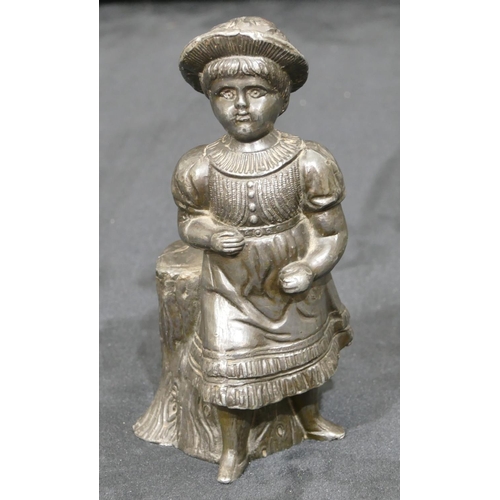 740 - A metal figure of a young girl standing next to a log, 14cm high