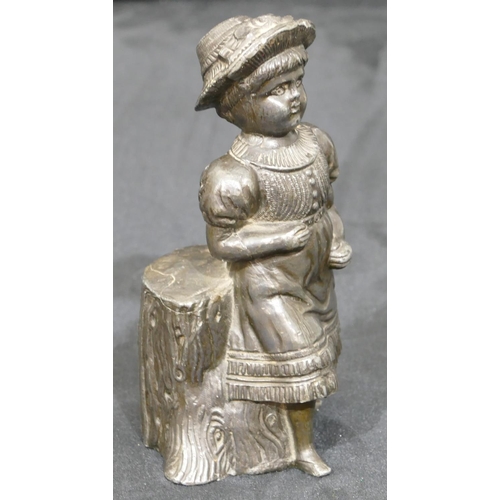 740 - A metal figure of a young girl standing next to a log, 14cm high