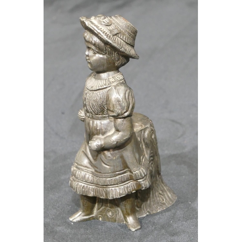 740 - A metal figure of a young girl standing next to a log, 14cm high