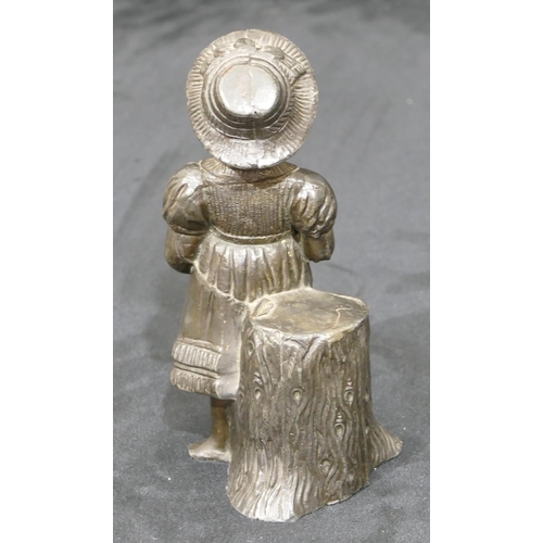 740 - A metal figure of a young girl standing next to a log, 14cm high