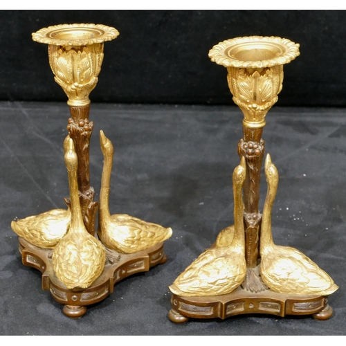 759 - A pair of bronze and ormolu candlesticks in the form of 3 swans on tripod base with bun feet, 17cm h... 