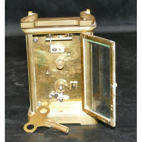 777 - A brass carriage clock with swing overhead handle, white enamel dial with Roman numerals (with key),... 