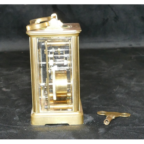 777 - A brass carriage clock with swing overhead handle, white enamel dial with Roman numerals (with key),... 