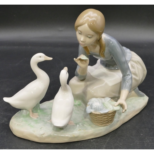 78 - A Lladro group of a kneeling young lady feeding 2 birds, 23.5cm wide.