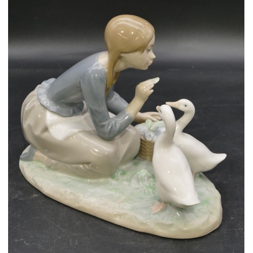 78 - A Lladro group of a kneeling young lady feeding 2 birds, 23.5cm wide.