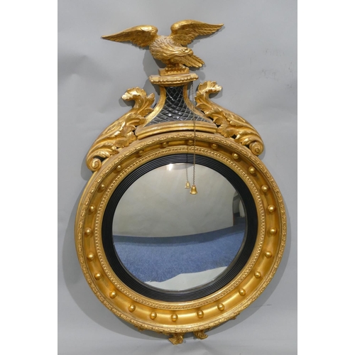 808 - An early 19th Century gilt and ebonised convex wall mirror with raised carved eagle motif and furthe... 