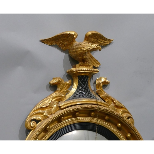 808 - An early 19th Century gilt and ebonised convex wall mirror with raised carved eagle motif and furthe... 