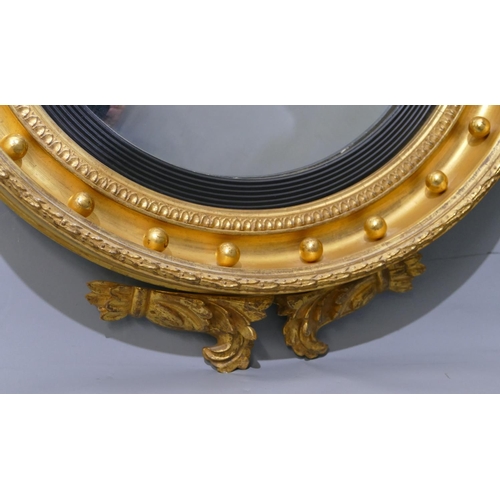 808 - An early 19th Century gilt and ebonised convex wall mirror with raised carved eagle motif and furthe... 