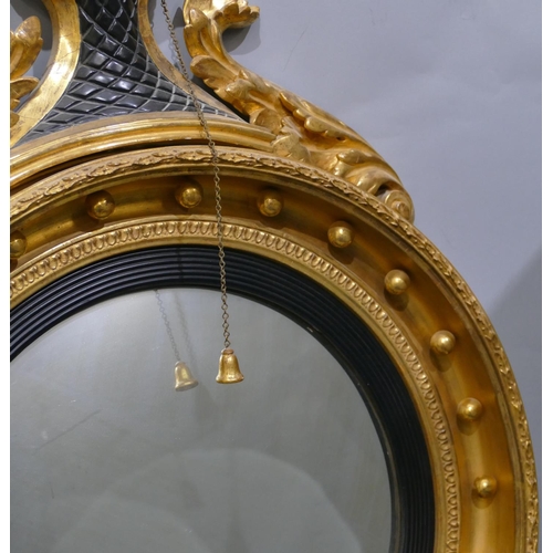 808 - An early 19th Century gilt and ebonised convex wall mirror with raised carved eagle motif and furthe... 