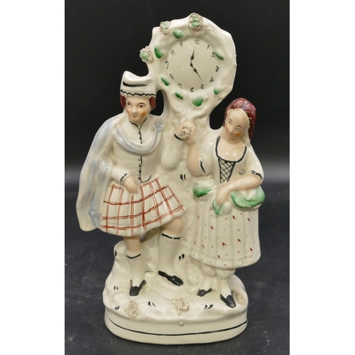 83 - A 19th Century Staffordshire clock group depicting Scottish gentleman and lady, 31cm high.