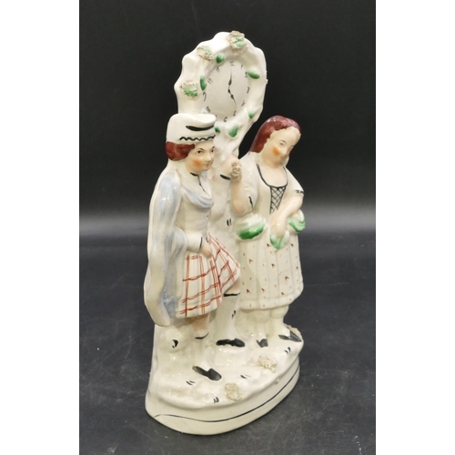 83 - A 19th Century Staffordshire clock group depicting Scottish gentleman and lady, 31cm high.