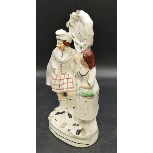 83 - A 19th Century Staffordshire clock group depicting Scottish gentleman and lady, 31cm high.