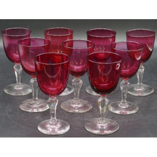 95 - A set of 9 ruby and clear drinking glasses with hexagonal stems on round bases, 13cm high.