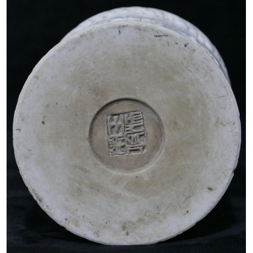 100 - An Oriental cylindrical brush pot on white ground with raised dragon and fish decoration, 12cm high