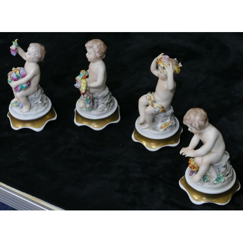 13 - A set of 4 Continental china figures of seated cupids with allover encrusted floral and bird decorat... 