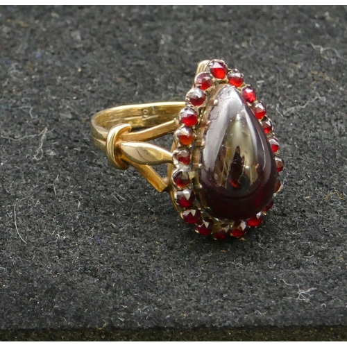 409 - A gold ladies cluster ring with centre pear shaped garnet, surround by smaller garnets, Size P, 6.3 ... 