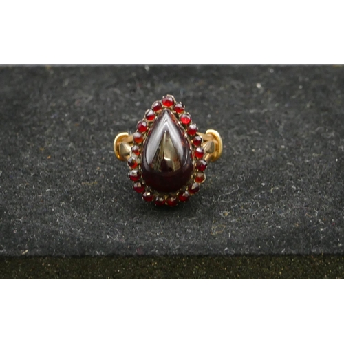 409 - A gold ladies cluster ring with centre pear shaped garnet, surround by smaller garnets, Size P, 6.3 ... 