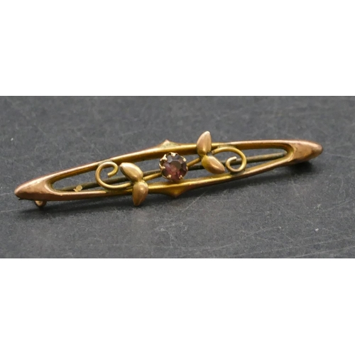 453 - A 9ct gold brooch with centre purple stone, raised leaf and scroll decoration, 1.2 grams gross.