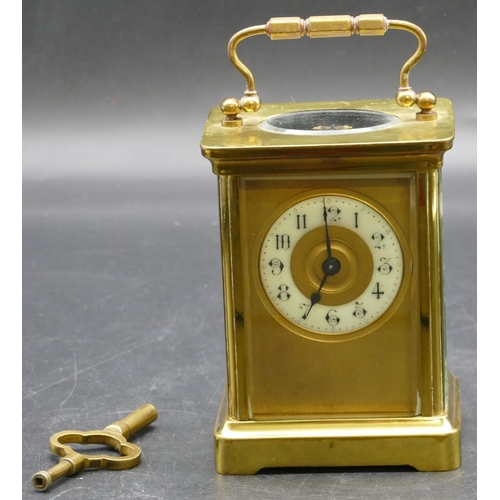 692 - A brass carriage clock with cream chapter ring with Arabic numerals, swing overhead handle (working)... 