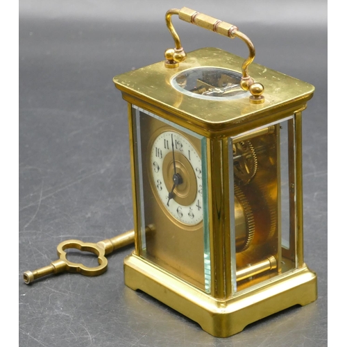 692 - A brass carriage clock with cream chapter ring with Arabic numerals, swing overhead handle (working)... 