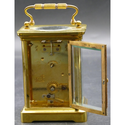 692 - A brass carriage clock with cream chapter ring with Arabic numerals, swing overhead handle (working)... 