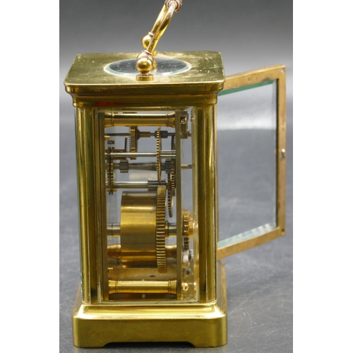 692 - A brass carriage clock with cream chapter ring with Arabic numerals, swing overhead handle (working)... 