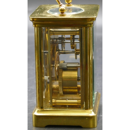 692 - A brass carriage clock with cream chapter ring with Arabic numerals, swing overhead handle (working)... 