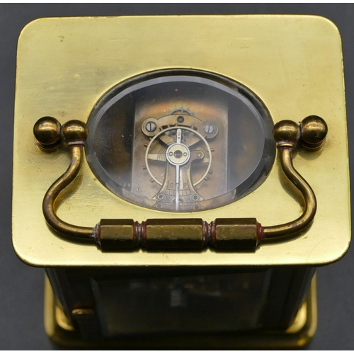 692 - A brass carriage clock with cream chapter ring with Arabic numerals, swing overhead handle (working)... 