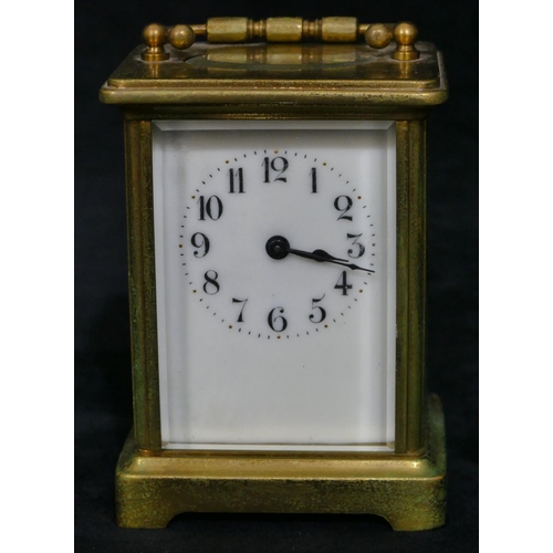 695 - A brass carriage clock with white enamel dial and Arabic numerals, swing overhead handle (over wound... 