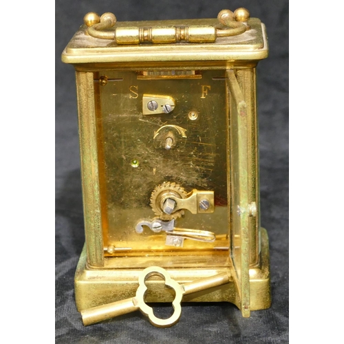 695 - A brass carriage clock with white enamel dial and Arabic numerals, swing overhead handle (over wound... 