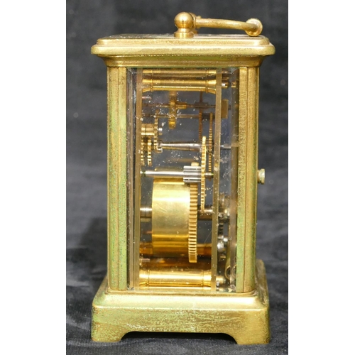 695 - A brass carriage clock with white enamel dial and Arabic numerals, swing overhead handle (over wound... 