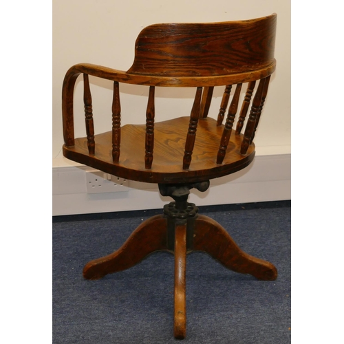 703 - An early 20th Century oak swivel desk chair with solid seat, turned finials, X-shaped base (no casto... 