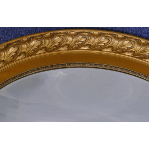 737 - An oval large gilt hanging bevelled wall mirror with raised leaf and scroll rim, 100cm wide, 75cm hi... 