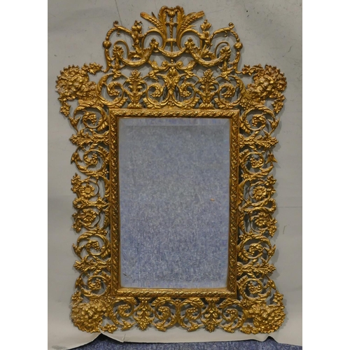 743 - A brass hanging bevelled wall mirror with pierced and raised figurehead, floral, leaf and scroll dec... 