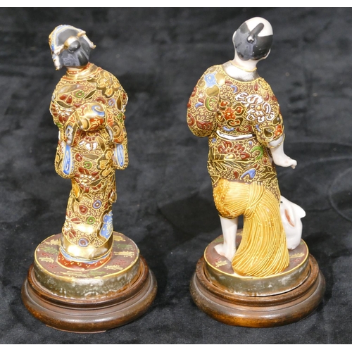 34 - A pair of Oriental figures of gentleman and lady with allover gilt decoration, on round wooden  base... 