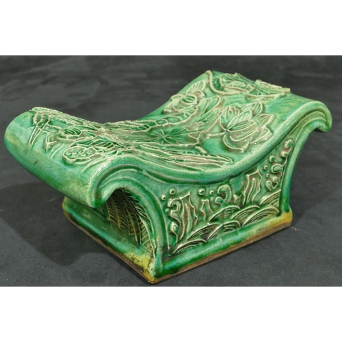 138 - An Oriental green glazed earthenware pillow with raised floral and leaf decoration, 23.5cm wide.