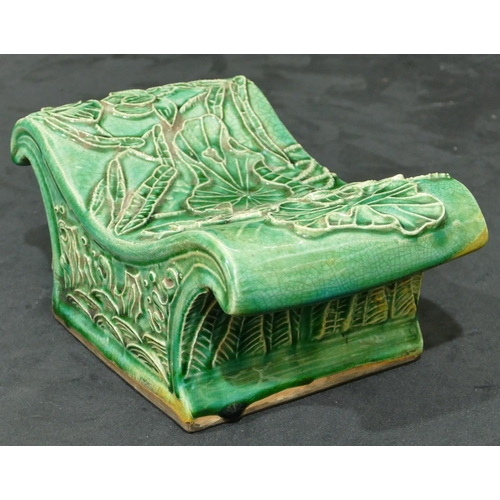 138 - An Oriental green glazed earthenware pillow with raised floral and leaf decoration, 23.5cm wide.