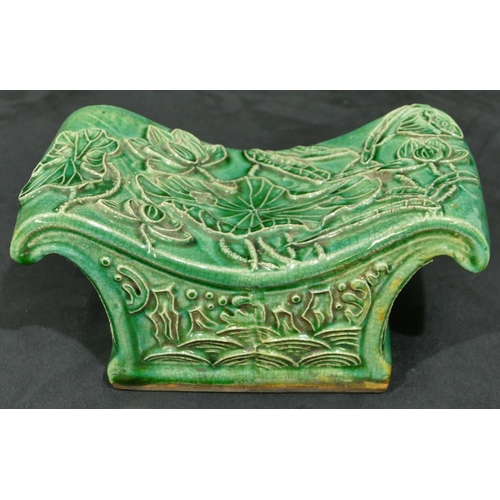 138 - An Oriental green glazed earthenware pillow with raised floral and leaf decoration, 23.5cm wide.