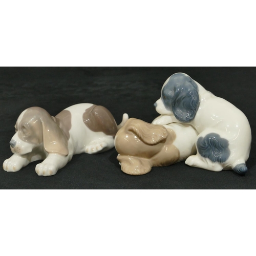 167 - A Lladro figure of a puppy on white and brown ground, 17cm wide, a Nao group of 2 puppies (2)