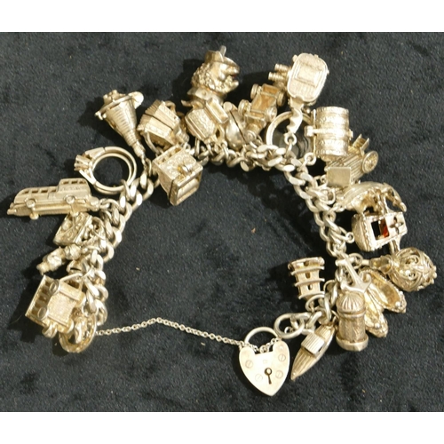 695 - A silver flat linked bracelet with padlock clasp, mounted with 25 silver charms, 121.4 grams