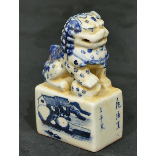 72 - An Oriental blue and white table seal in the form of dog of fo seated upon plinth with landscape dec... 